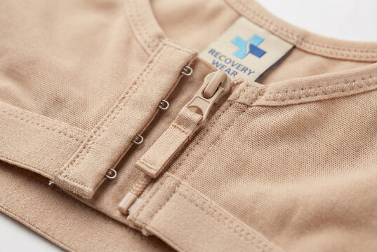 Close-up of beige post-surgical recovery bra with front zipper and hooks for breast surgery healing