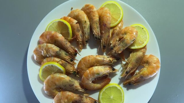 Boiled unshelled king prawns with lemon slices on white plate