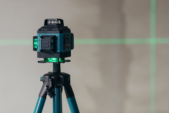 Laser Level Projecting Cross Lines On Wall. Precision Instrument For Alignment And Leveling.