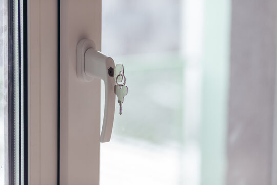 Window Handle With Keys Inserted In Lock. Security And Access Detail In Interior Setting.