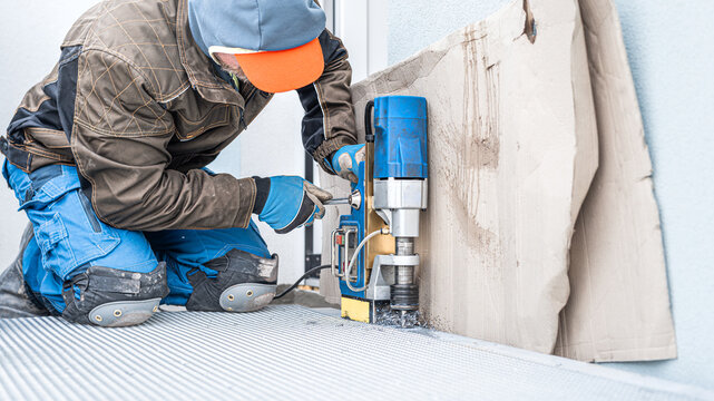 Assembly of prefabricated steel staircase. Worker drilling to the U - steel beam using magnetic core drill.