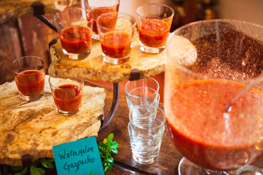 Glasses of watermelon gazpacho arranged on rustic wooden platforms on a table