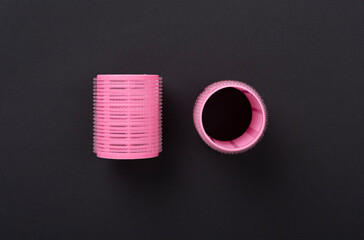 Pink hair curlers on color background, top view