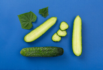 Flat lay with cucumber with leaves and flowers on color background