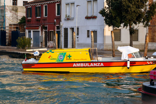 Venice, Italy - February 07, 2026: Ambulance boat labeled "AMBULANZA" navigating through water in Venice, Italy, with buildings and trees visible along the canal