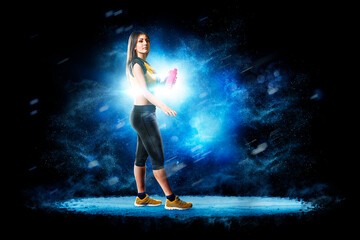 Fitness. Professional female fitness against a beautiful black background with a flash of light behind her. Isolated on a black background. © 103tnn