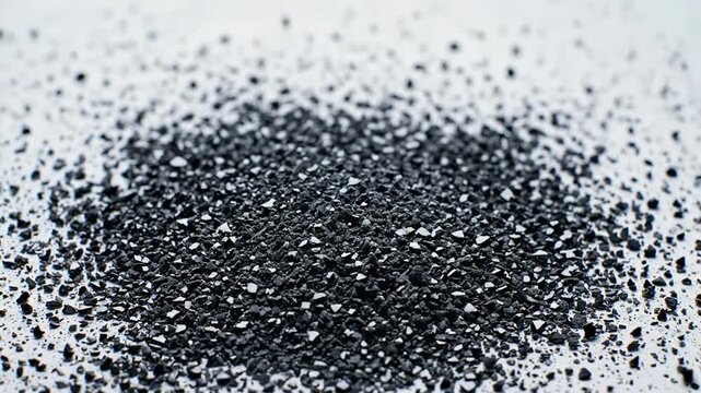 Slow motion emergence of countless minute black fragments rising up from a solid white surface creating a dense geological speckled pattern and then settling settling, particles, construction