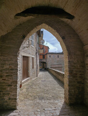Fototapeta premium Ancient stone arch and vaulted walkway Le Copertelle in Serra San Quirico, Marche, Italy. Historic medieval alley with cobblestones and old walls