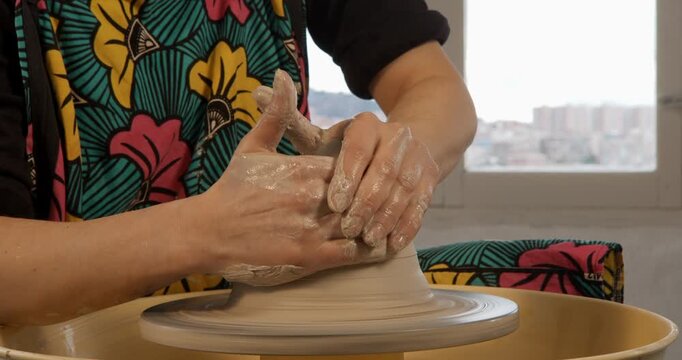 Hands shaping Clay: A pair of hands meticulously shapes a lump of wet clay on a pottery wheel, transforming it into a piece of art, showcasing the skill and patience involved in pottery.