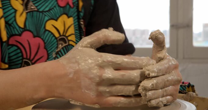 Artisan's Touch: A close-up view of hands meticulously shaping wet clay on a pottery wheel, transforming a raw lump into a vessel of art and functionality, embodying the essence of creation.