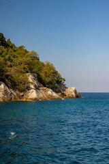 Naklejka premium Uninhabited island with rocky shore and clear sea. Concept: untouched nature and ecology.