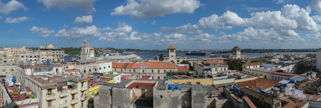 Aerial cityscape panoramic view of Havana City harbour, colorful facades of old colonial buildings and shingled roofs, sunny day, blue sky with white clouds.