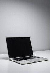 solo laptop sits minimalist white surface backlit soft overhead light dark screen reflecting surrounding
