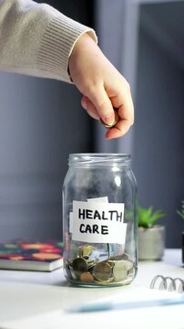 Health goal savings in labeled jar. Person contributing to Healthcare fund jar, representing wellness investment and proactive approach to medical expenses