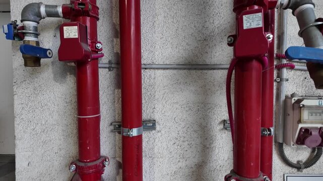 Industrial fire suppression sprinkler system installed on a warehouse ceiling. Red fire protection pipes, sprinkler heads and water distribution network designed for automatic fire safety response. Mo