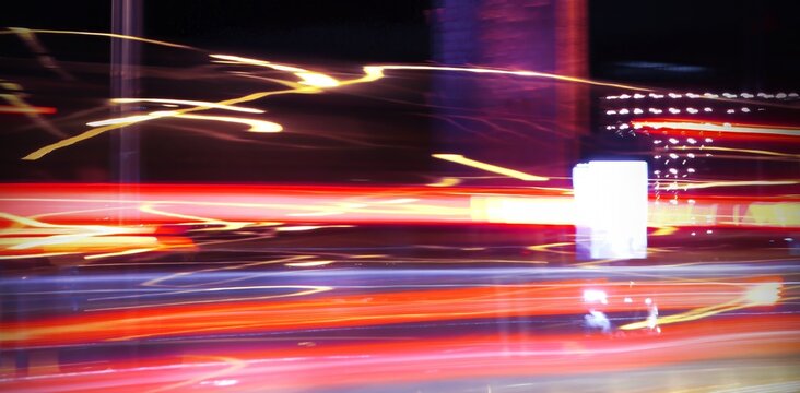 Abstract background. Colorful night street photography. Long exposure. Motion effect. Moving cars. Composition of light lines in perspective. Selective focus. Beautiful bokeh. Soft image.