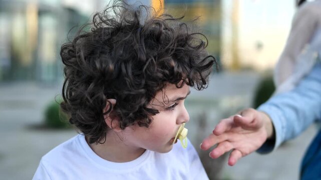 A mother tries to take a pacifier away from her grown-up child. The concept of saying goodbye to pacifiers in children.