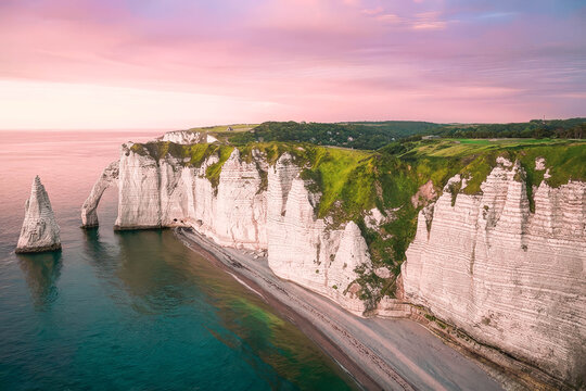 View of the white chalk cliffs of Etretat with natural arch and sea stack at sunset, Normandy, France