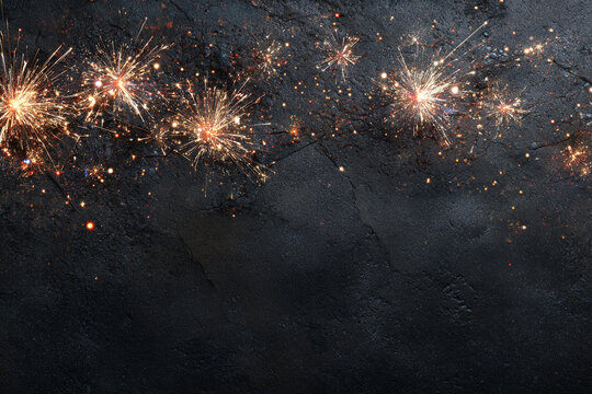 Sparkling fireworks illuminate a dark textured surface with a festive glow