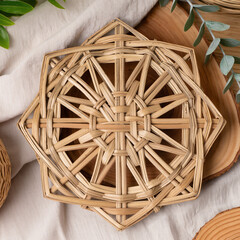 Eco friendly home decor with handcrafted rattan wicker coaster on wooden tray placed on light fabric background with eucalyptus leaves and natural textures