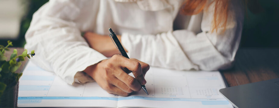 Planner plan Schedule Calendar and reminder agenda, work online at home. Women hand writing daily appointment and note holiday trip in diary at business office desk. Calendar reminder event concept.