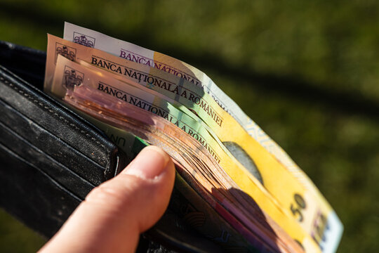 Man hand holding a wallet with Romanian LEI banknotes showing paper texture and symbols of Romanian currency