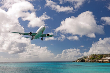 Obraz premium Jet airplane landing over turquoise ocean near tropical coast