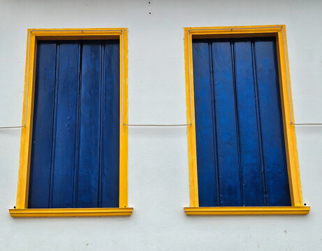 Large wooden window in blue, in the style of a colonial house, a unique architectural style, typical of a rustic city.