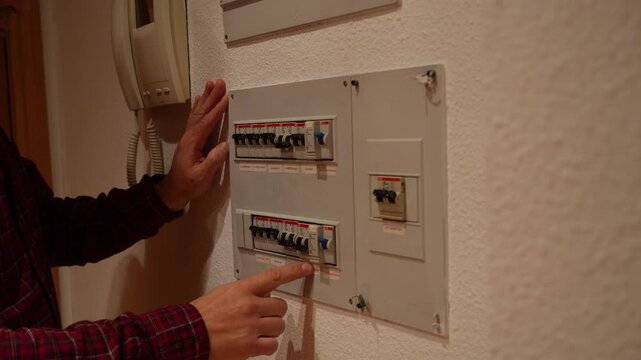 A man pick up the circuit breakers from the electrical panel in his home.