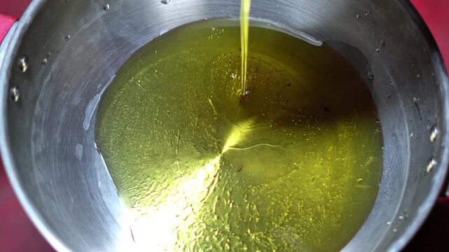Pouring Cooking Oil into Metal Bowl Close Up &ndash; Food Ingredient Preparation. Fresh Cooking Oil Being Poured into Metal Pot. Liquid Edible Oil Pouring - Kitchen Cooking Concept.