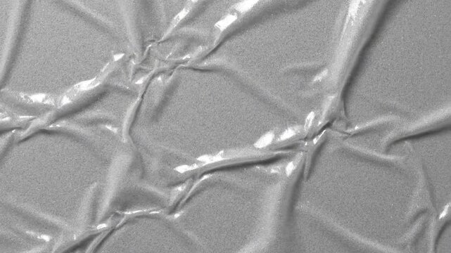Gray wrinkled plastic sheet with reflective surface texture.