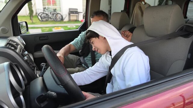 Father teaching his teenage son how to insert the key into the car ignition.