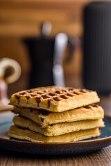 Sweet waffles with chocolate on plate on wooden table.