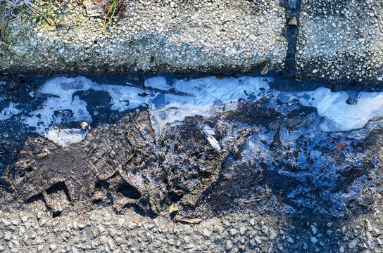 Close-up of icy mud and gravel on a cold winter day with frost on the edges