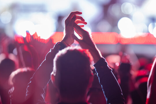 Man clapping at concert with crowd cheering and stage lights