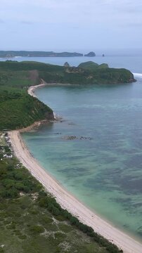 Aerial Green Island Cape With Curved Beaches, Rolling Hills And Farmland Pockets, Long Reef Line Shaping Waves, Secluded Bays, Turquoise Shallow Water Meeting Deep Ocean, Katil beach,Lombok,Indonesia