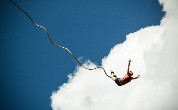 woman bungee jumping against blue sky