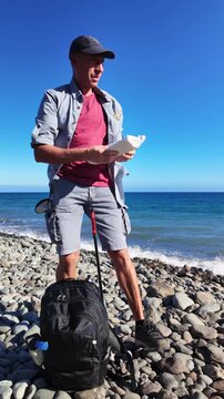Slow motion footage of a man volunteering and collecting garbage on a rocky beach, putting it into a bag to clean the environment and fight ocean pollution for World Environment Day