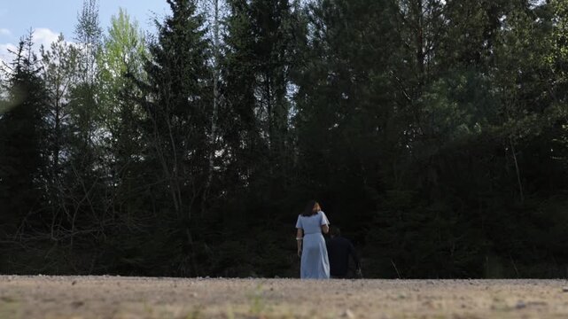 A loving couple in summer clothes walks through a summer park field in nature.v