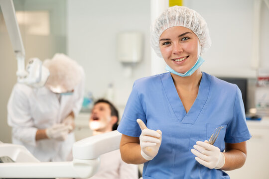 Young girl doctor in blue suit cooperates with clinic, works as general practitioner in dental department of clinic. Doctor enjoys working in profession.