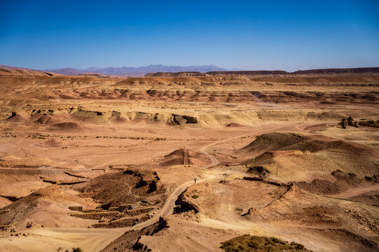 Arid desert landscape with rolling hills and Atlas mountains, Ait Benhaddou, Morocco.
