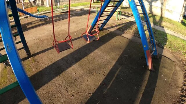 The metal swingset features two wooden seats painted in bright blue and red