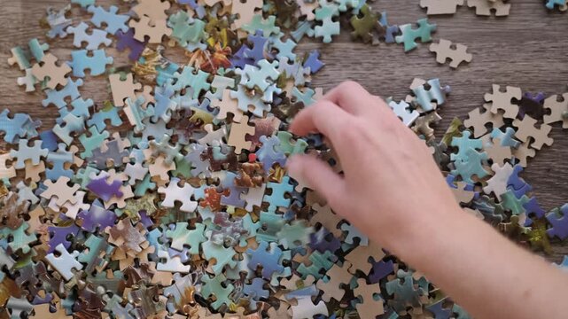 Person's hand searching through jigsaw puzzle pieces