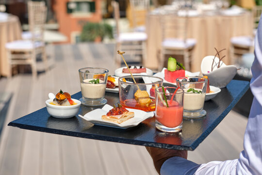 Waiter carrying elegant appetizers and drinks tray at event