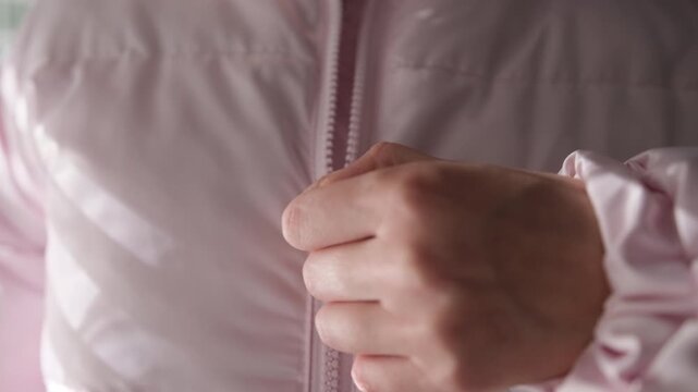 Woman's hand unzipping pink puffer jacket