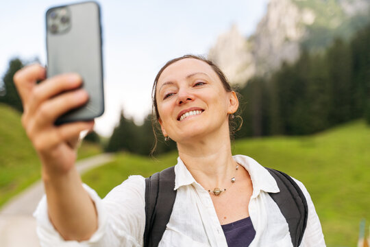 Woman smiling while taking a selfie in nature