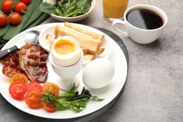 Tasty breakfast with soft boiled eggs and bacon served on grey table, closeup. Space for text