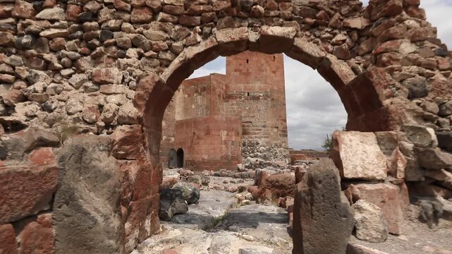 Discover the majestic ruins of Dashtadem Fortress in Armenia. The video showcases the medieval architecture, prominent red tuff stone walls, and a beautiful ancient archway against cloudy skies.

