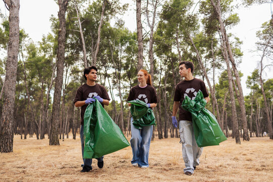 Volunteers in forest collecting trash in recycling bags