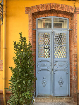 Charming blue door with brick arch and yellow wall
